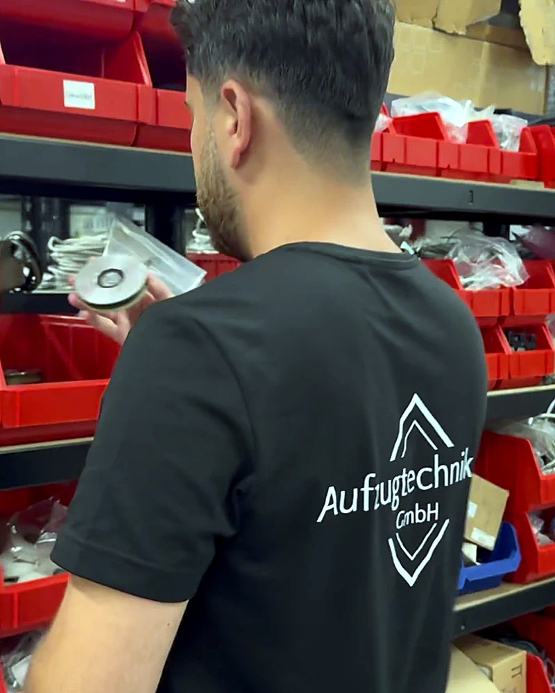 Servicetechniker der Aufzugtechnik LR prüft ein Ersatzteil im Lager